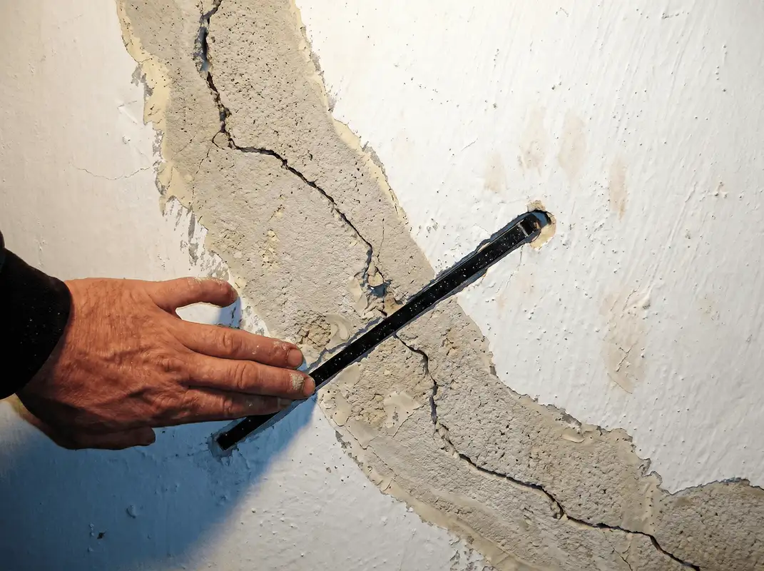 A wall with a large crack is being inspected by a professional in Phoenix, AZ